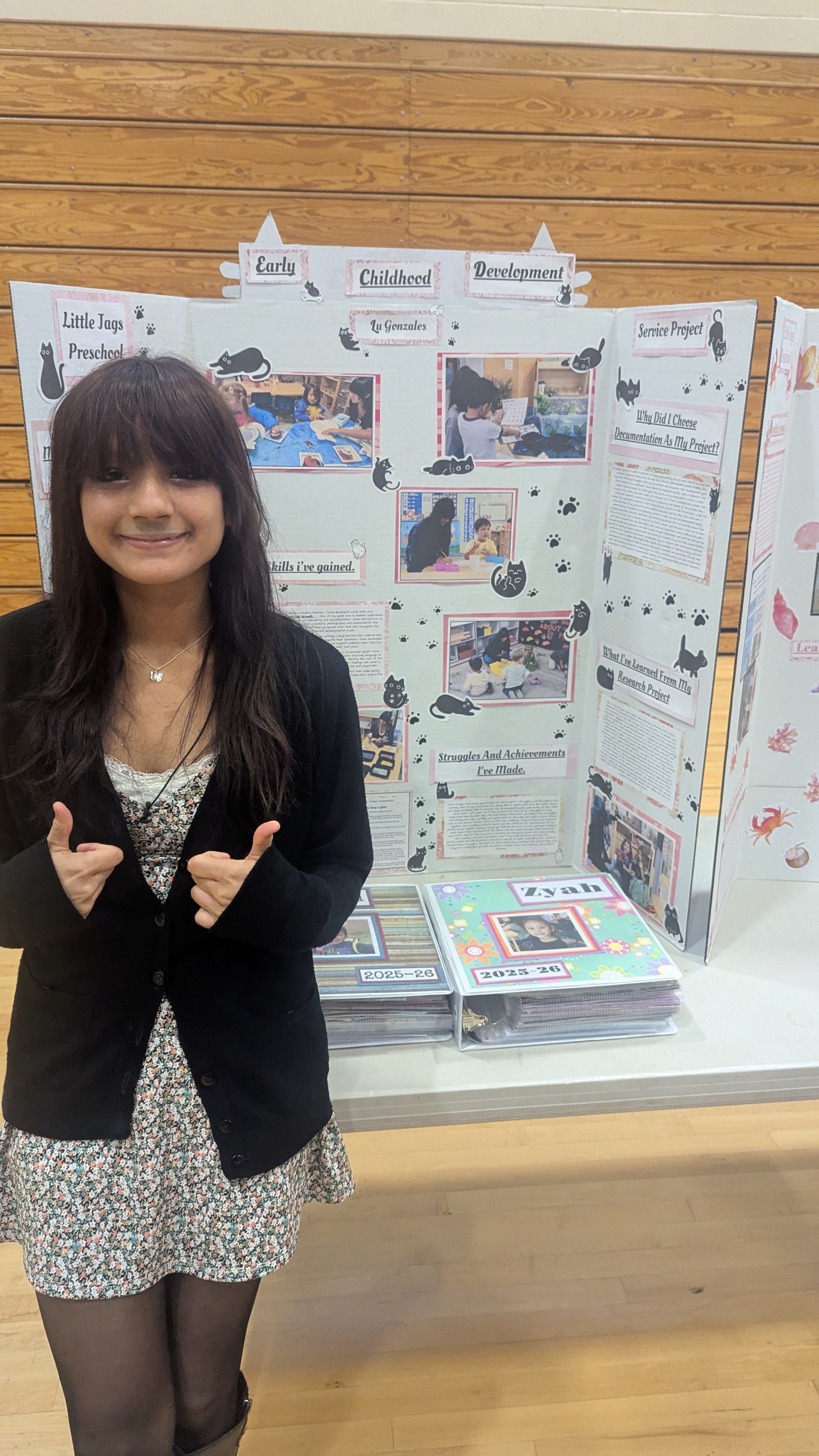 Lu in front of her Early Childhood Development senior project tri-fold board